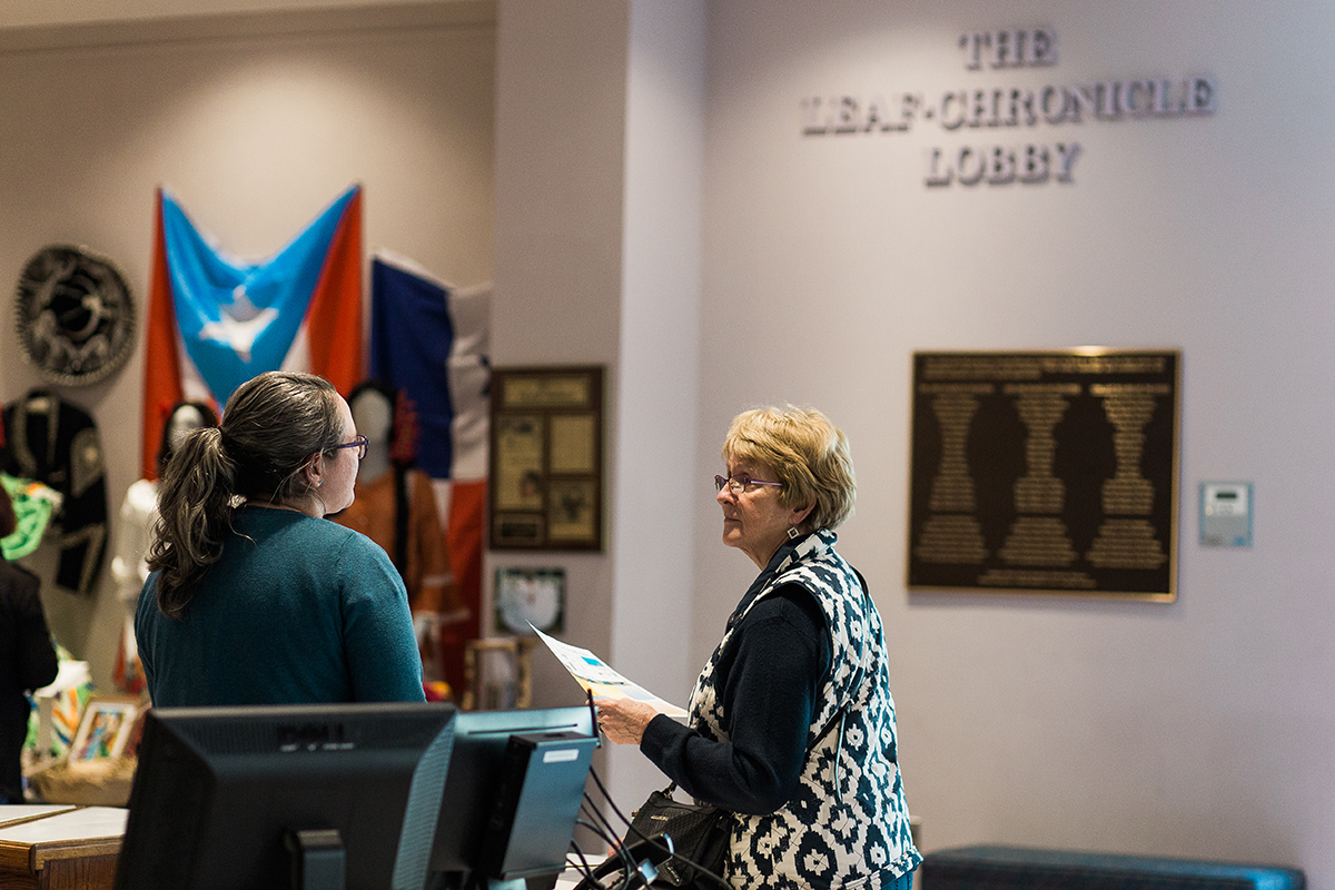 A Museum visitor talks to the front desk associate in the lobby of the Museum.