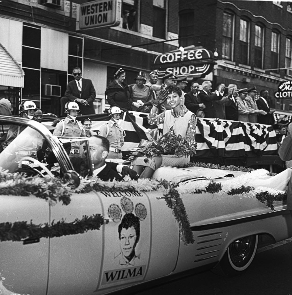Wilma Rudolph sits in a decorated car and rides through downtown Clarksville during her welcome home celebration parade.
