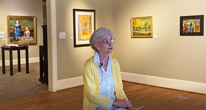 Screenshot of video. Dee Boaz sitting in Jostens Gallery.