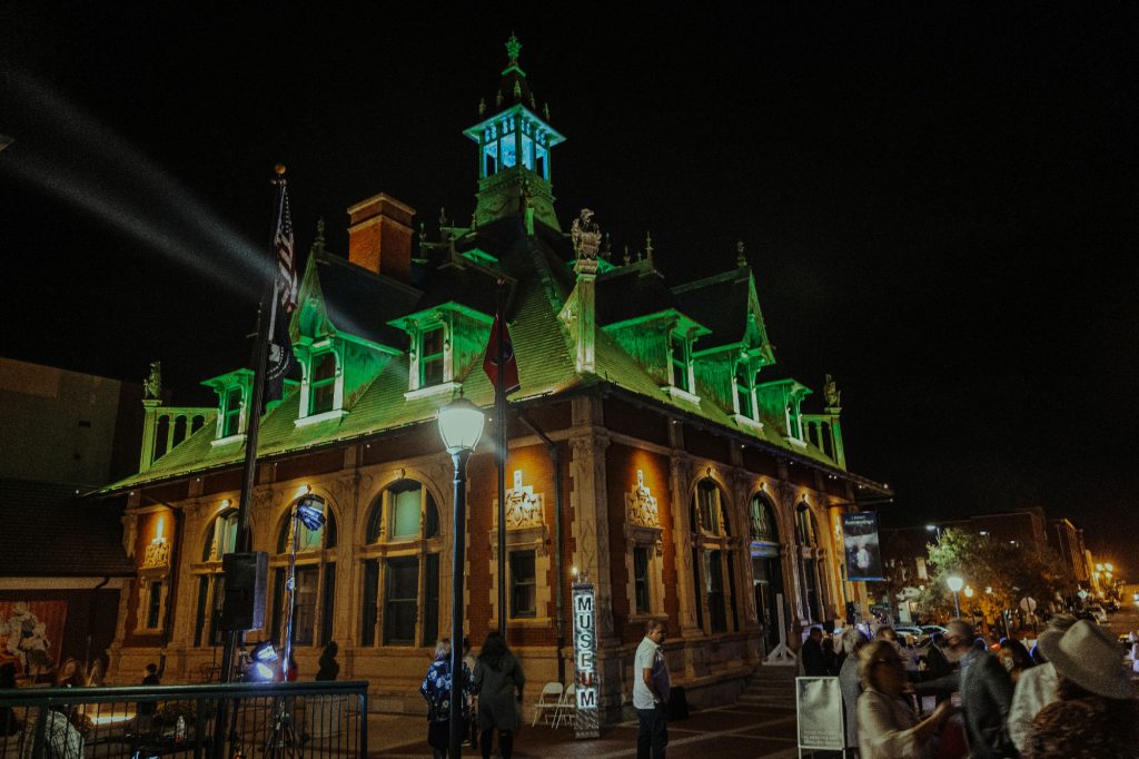 The Customs House Museum & Cultural Center illuminated in green for the crowd.