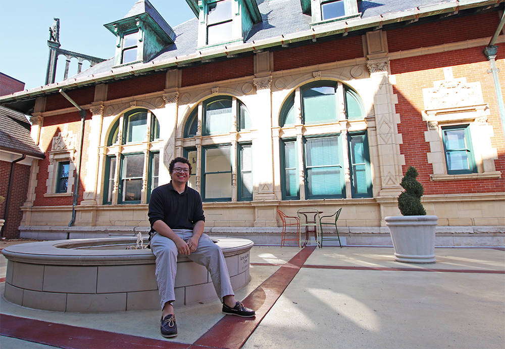 Marketing Intern Alijah Poindexter sits on the fountain in the courtyard of the Customs House Museum & Cultural Center