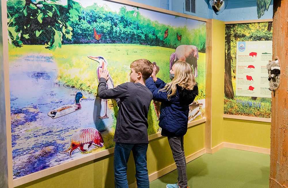 two children play in explorers landing at the magnetic nature wall.